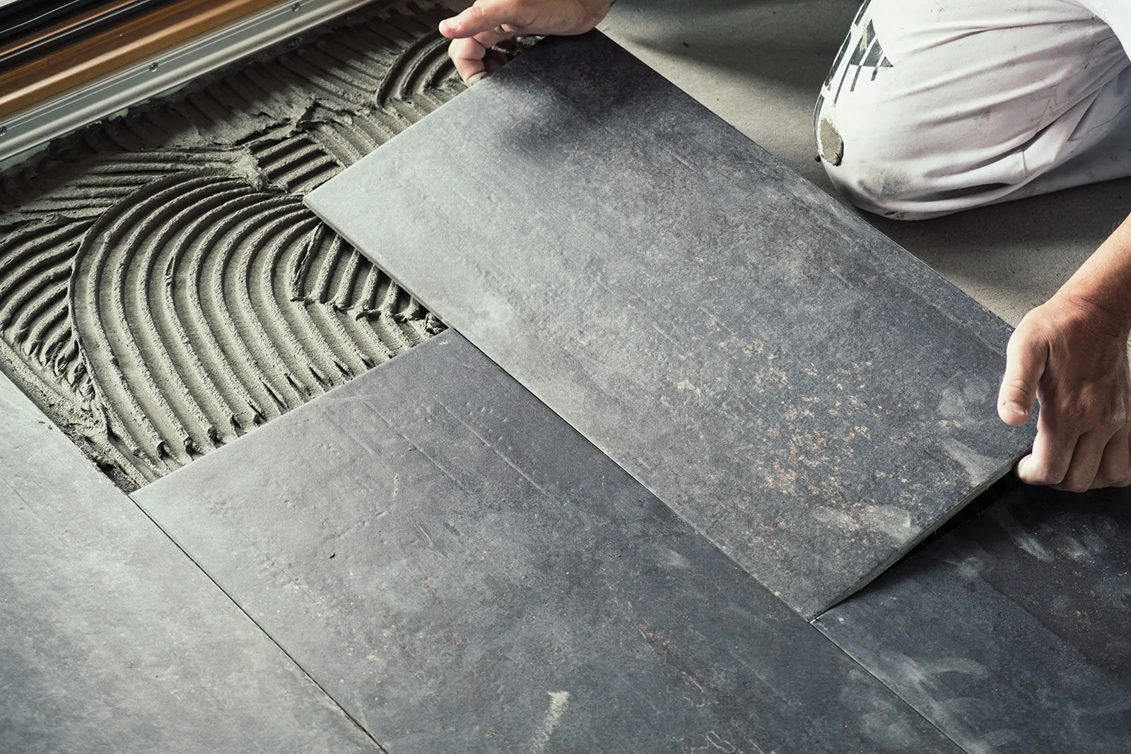 Plattsättare lägger stora klinkerplattor i fix under en badrumsrenovering